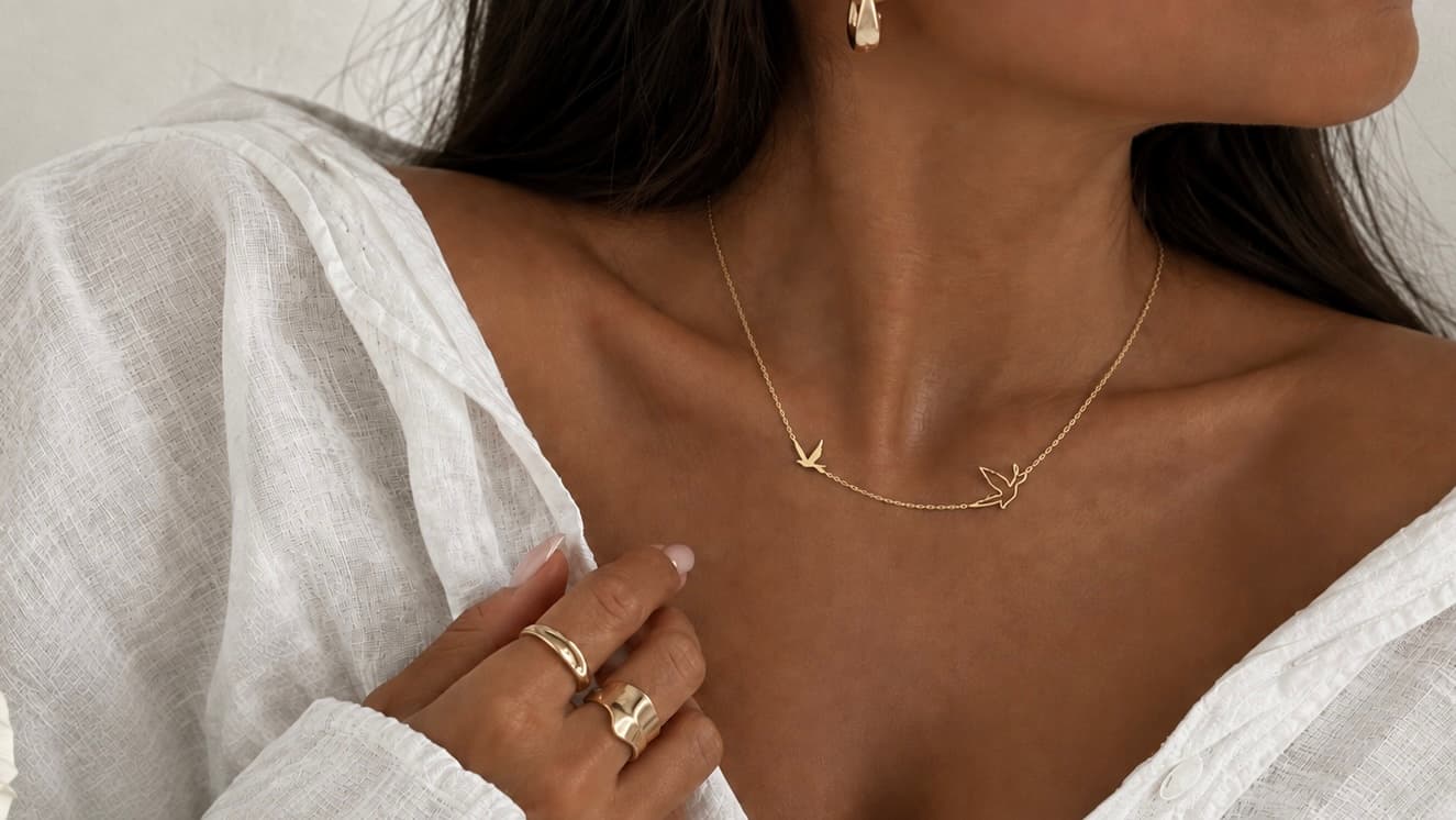Portrait porté : collier hirondelles, créole et bagues empilées